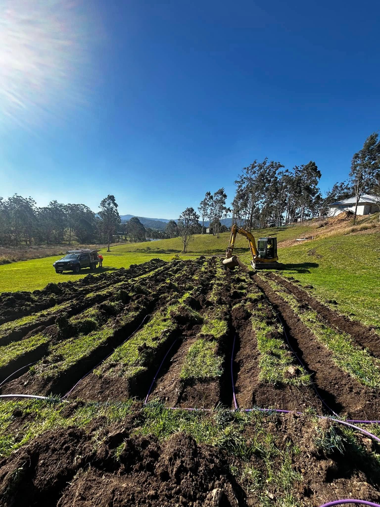 A Large Field of Dirt and Grass with A Tractor in The Background — Matt King Plumbing & Septic Systems in Taree, NSW
