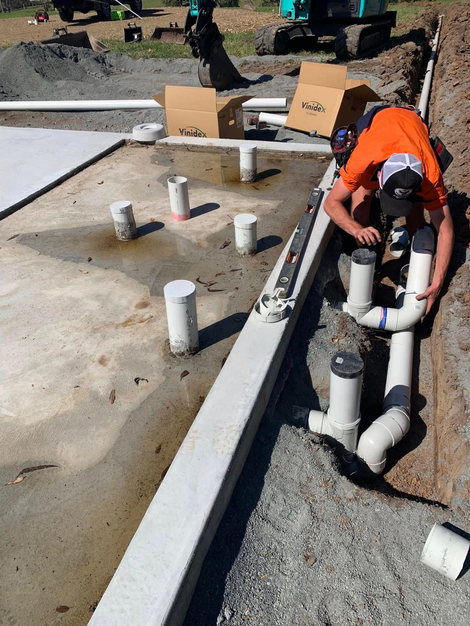 A man is working on pipes on a construction site — Matt King Plumbing & Septic Systems in Taree, NSW