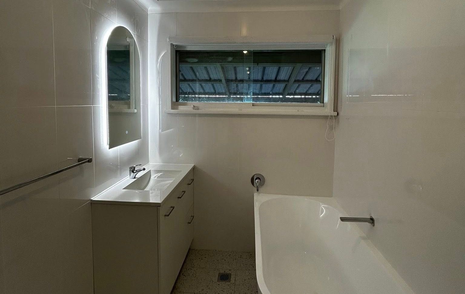 A bathroom with a sink , tub , mirror and window — Matt King Plumbing & Septic Systems in Wauchope, NSW