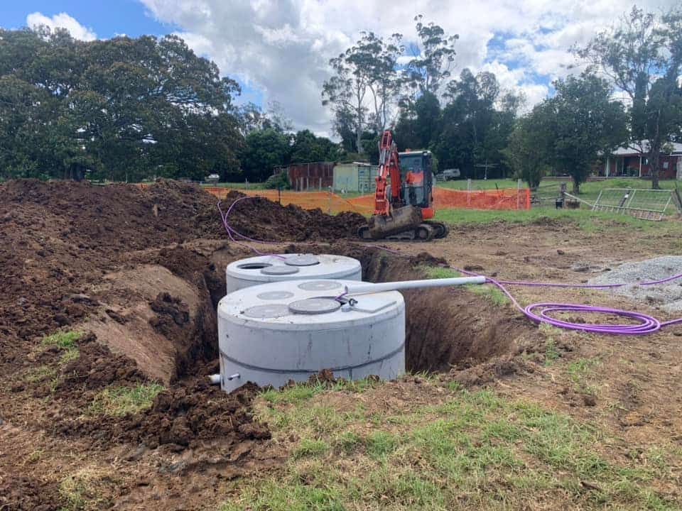A Concrete Septic Tank Is Being Installed in A Dirt Field — Matt King Plumbing & Septic Systems in Taree, NSW