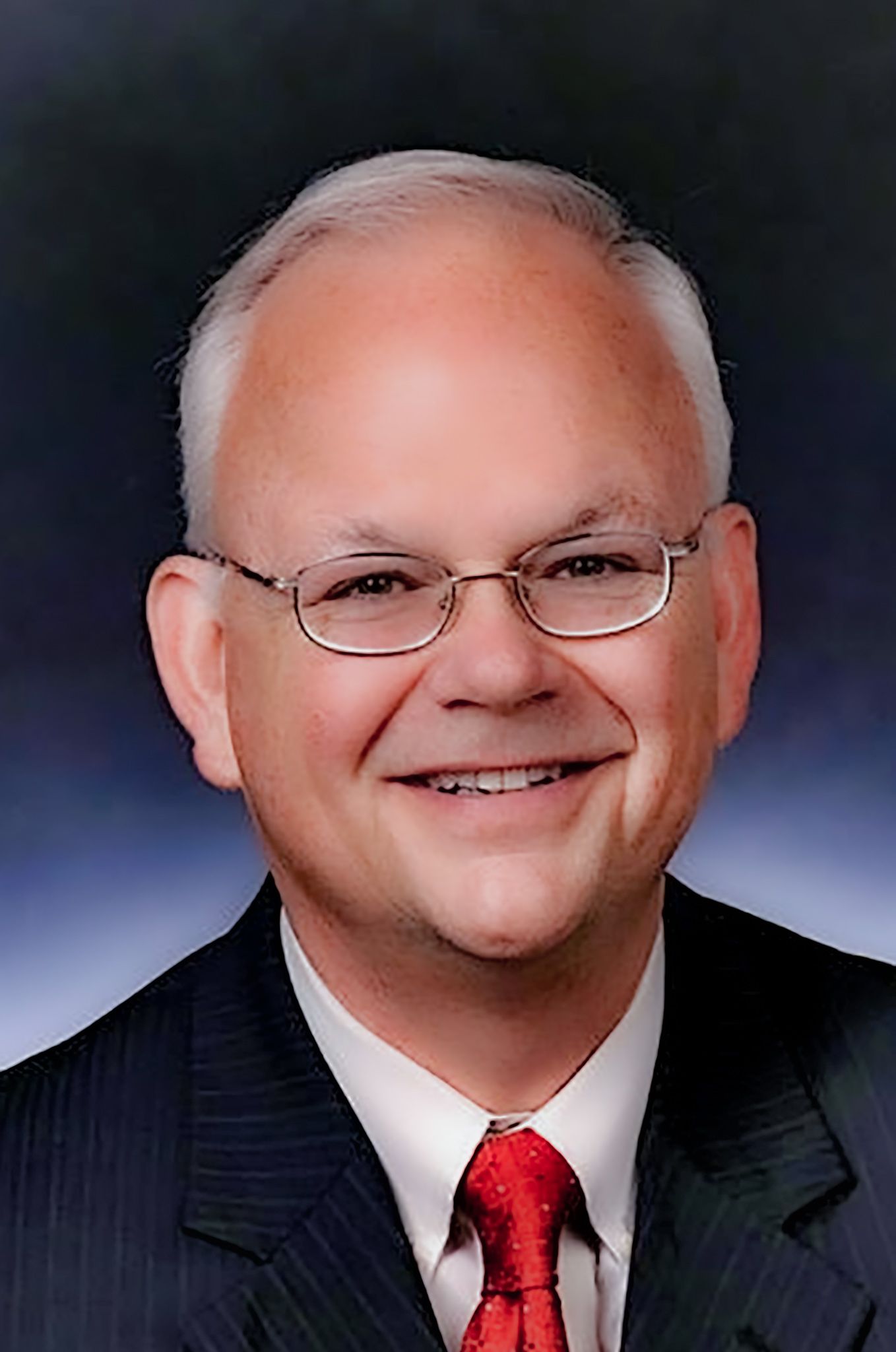 A man in a suit and tie is smiling for the camera