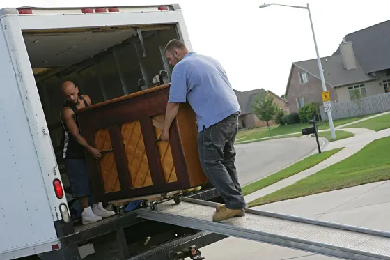 Two people loading a piano into a truck using a ramp. Two people loading a piano into a truck using a ramp.
