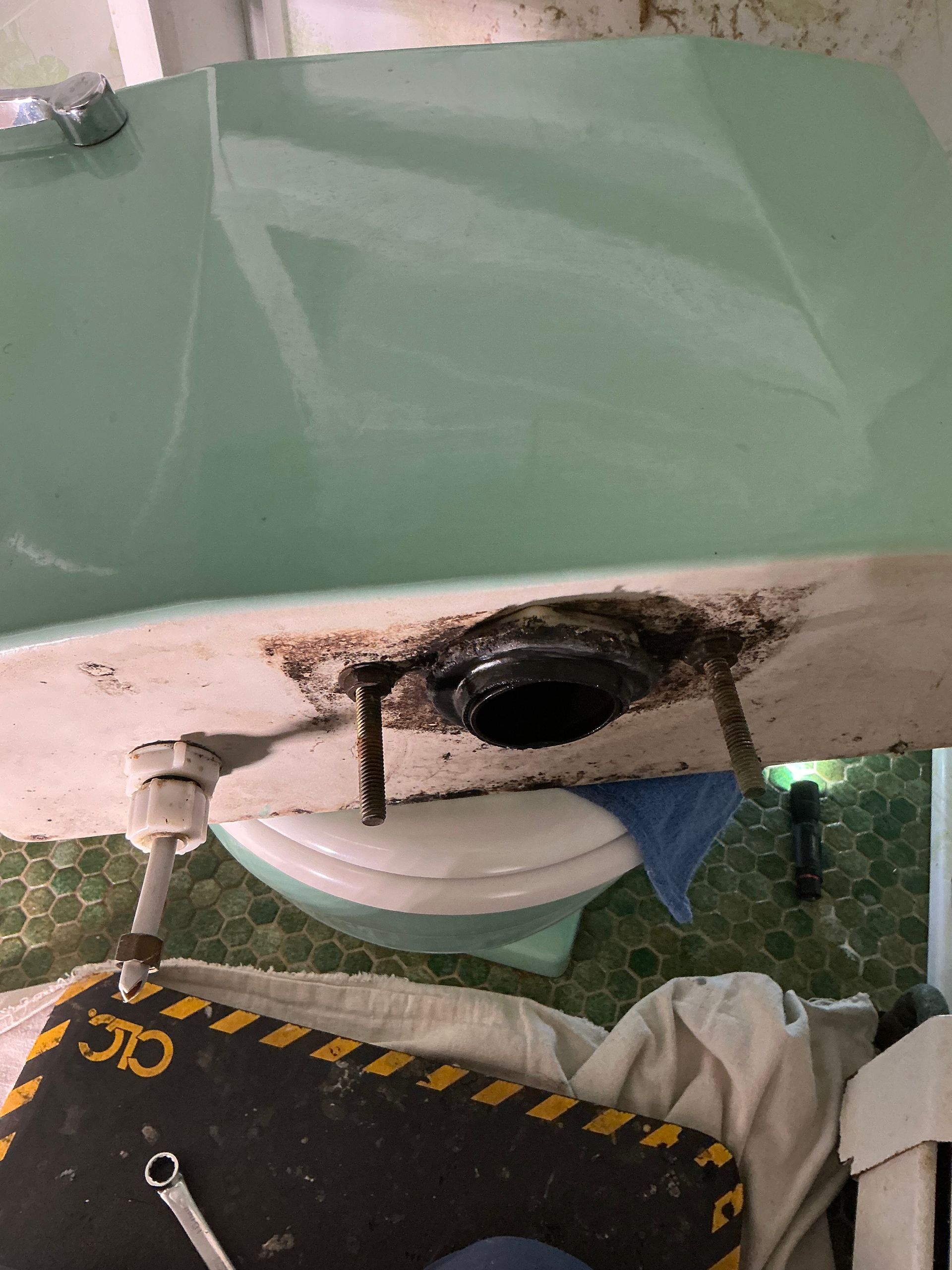 Bathtub drain exposed, repair in progress; green tub, plumbing, tools on work mat.