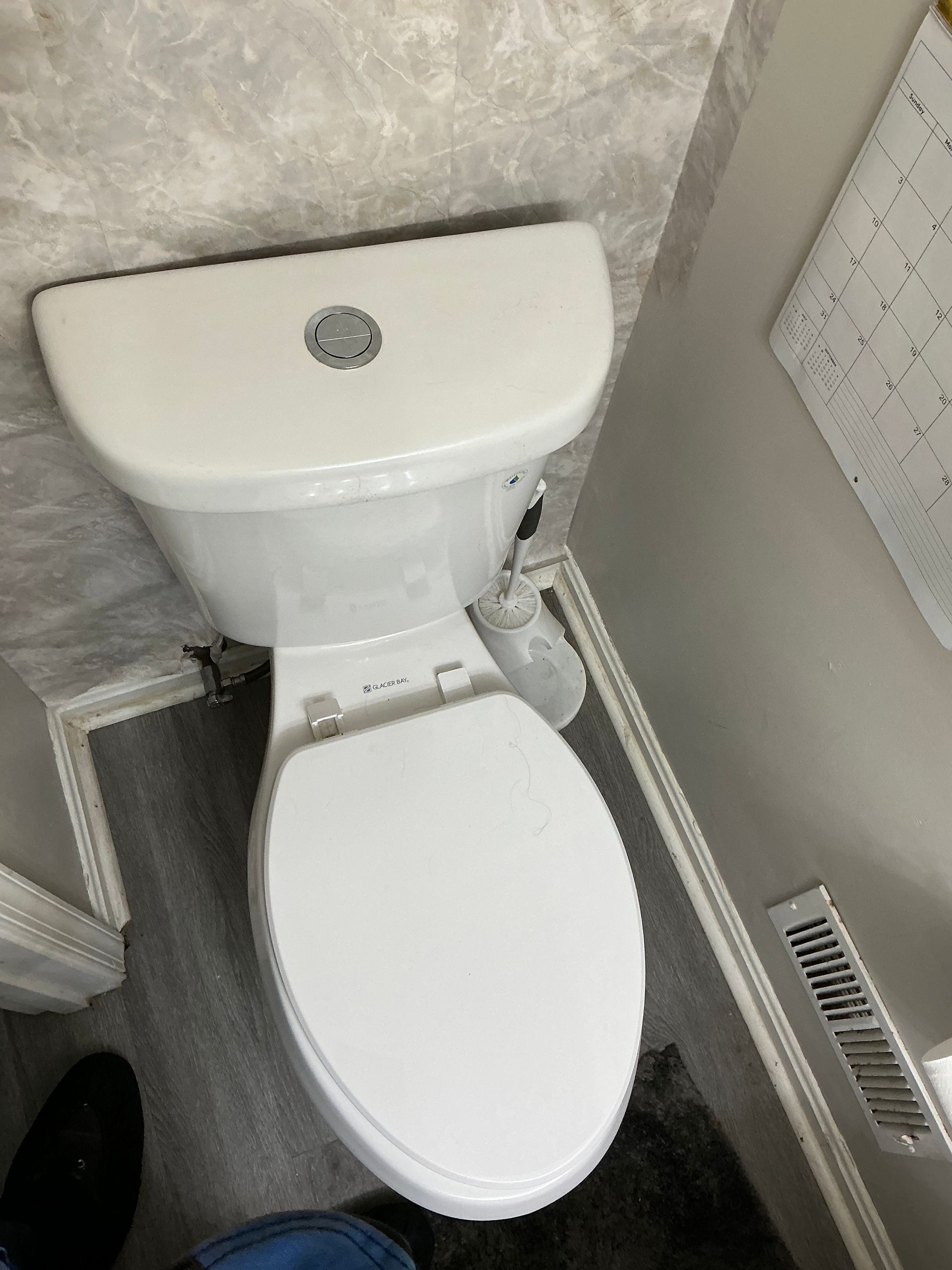 White toilet in a bathroom with gray walls and flooring.