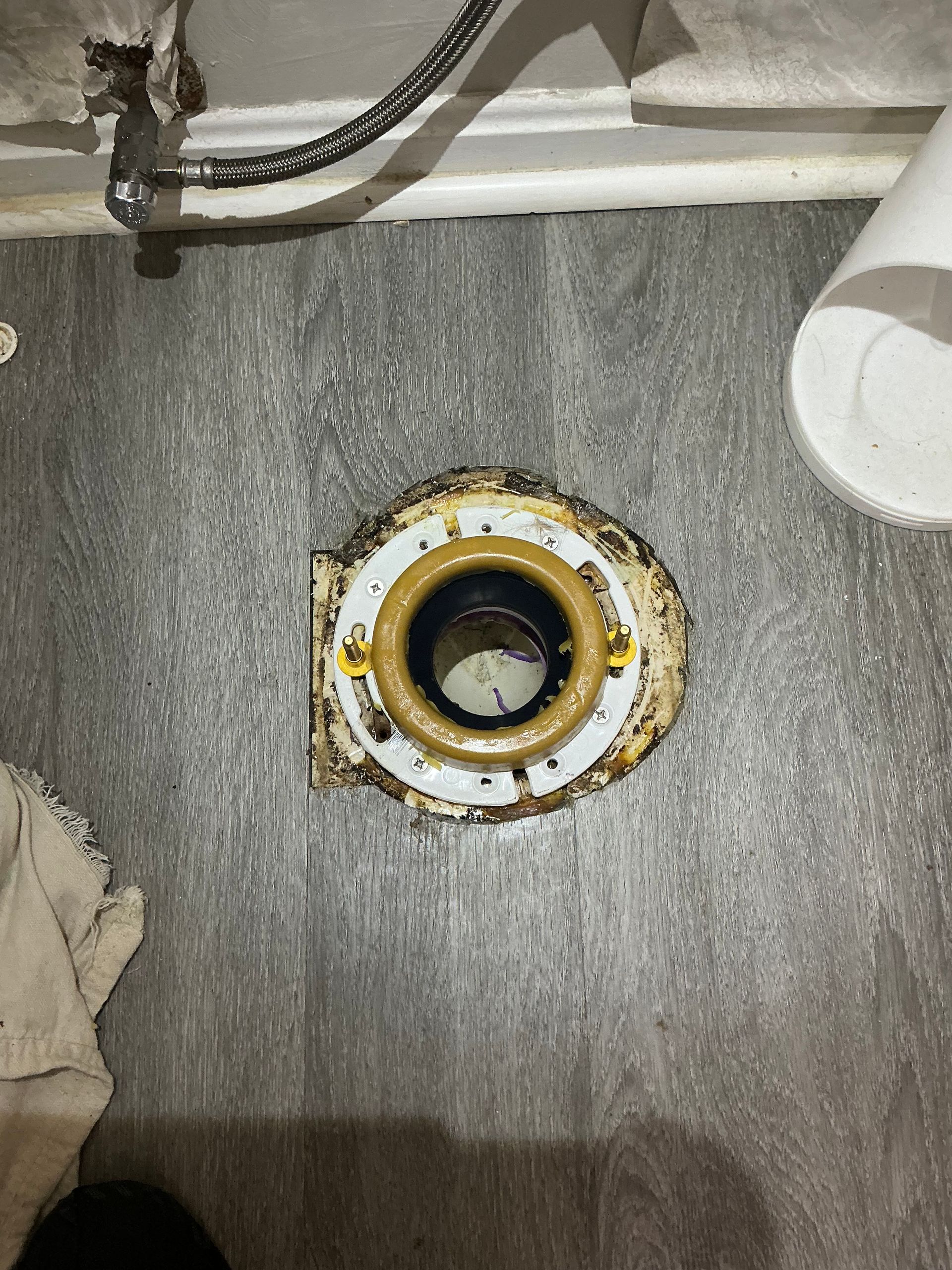 Toilet flange on gray floor with a wax ring in the center.