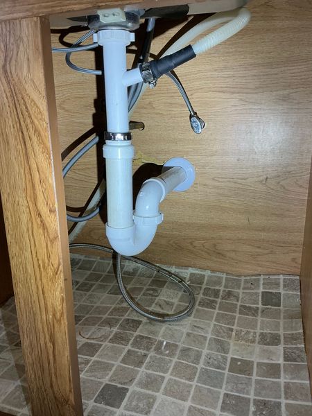 Two silver water faucets with red handles mounted on a white wall.
