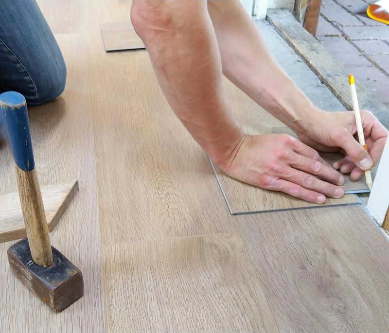 A person is measuring a piece of wood with a pencil