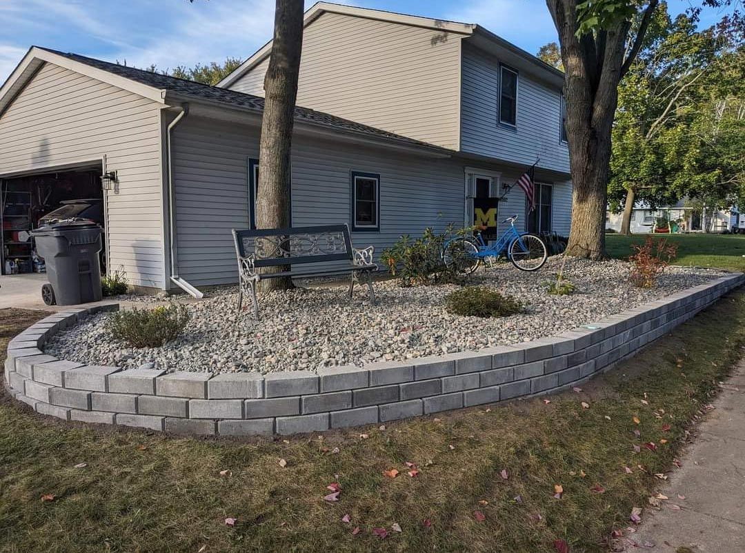 A house with a brick wall and a bench in front of it.