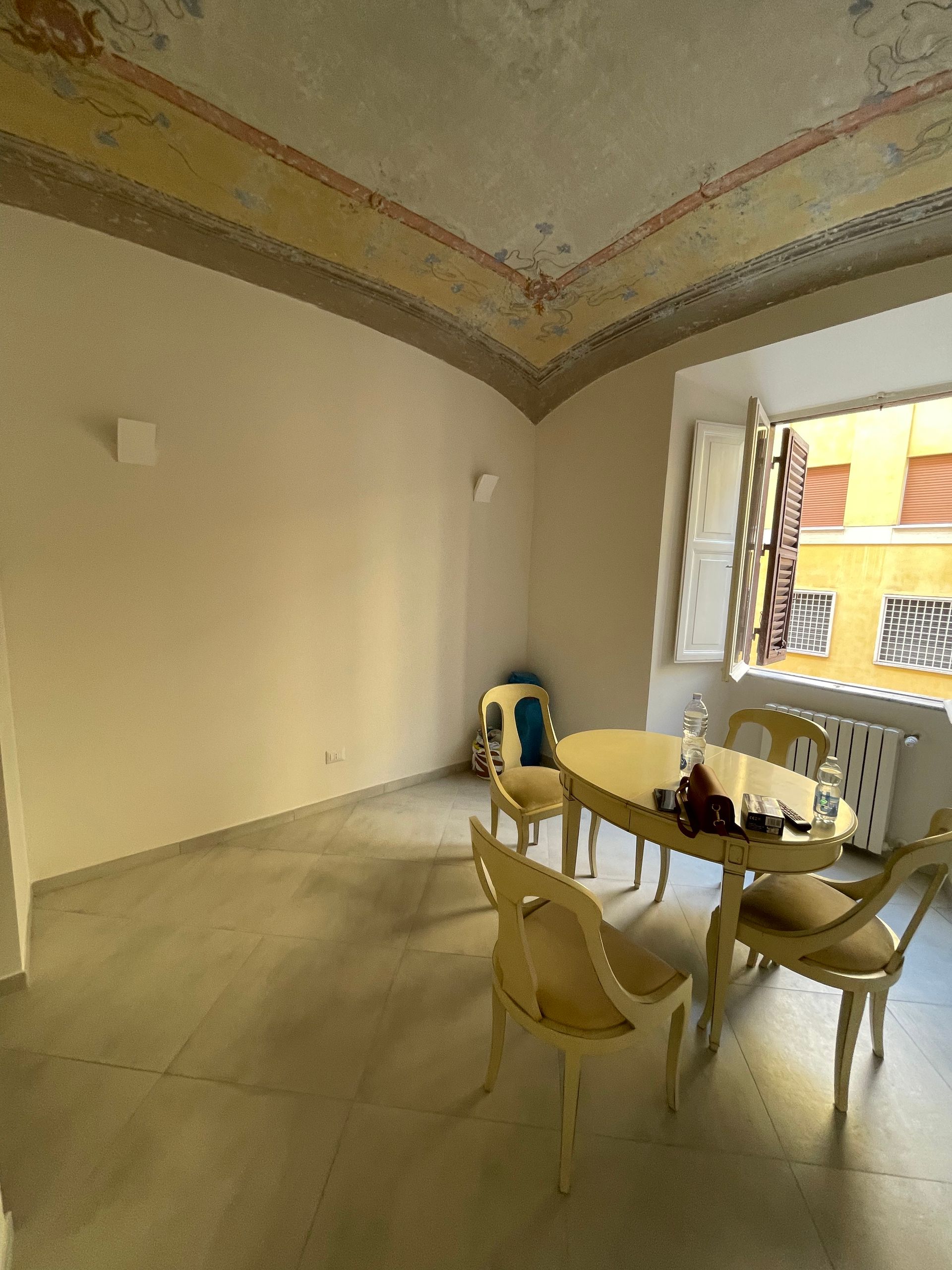 Soggiorno ristrutturato con un perfetto equilibrio tra elementi storici e design moderno, valorizzato da una luce naturale che esalta gli affreschi.