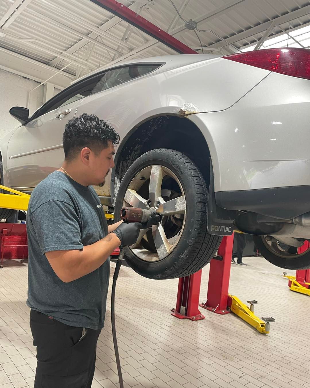 A mechanic removing a wheel from a silver car raised on a lift | Righteous Auto Care