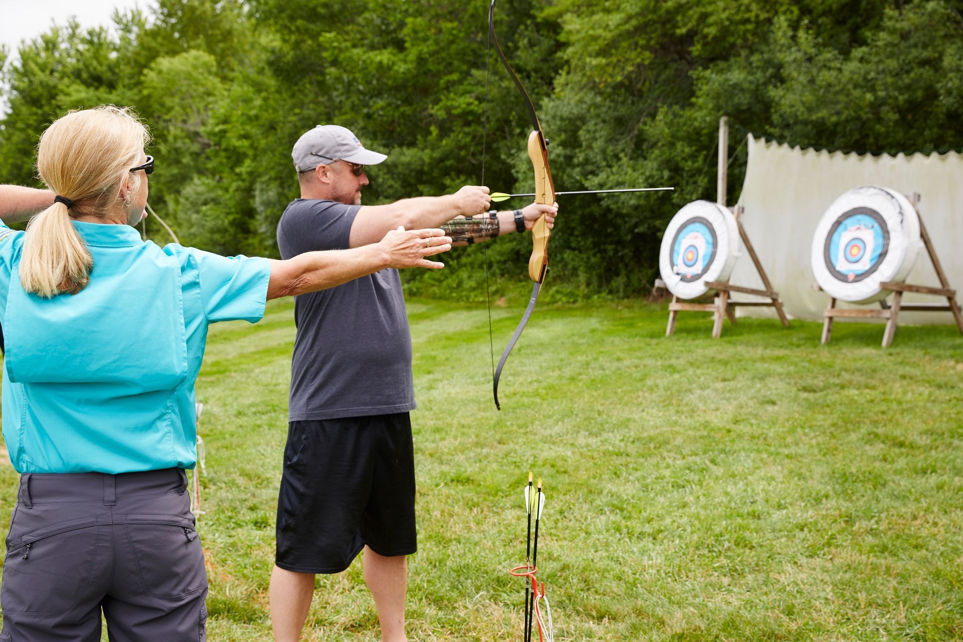 Instructor coaching a participant with proper archery form and technique