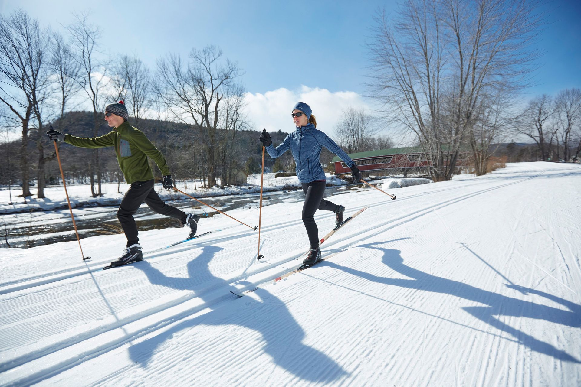 A man and a woman cross-country skiing on a groomed trail