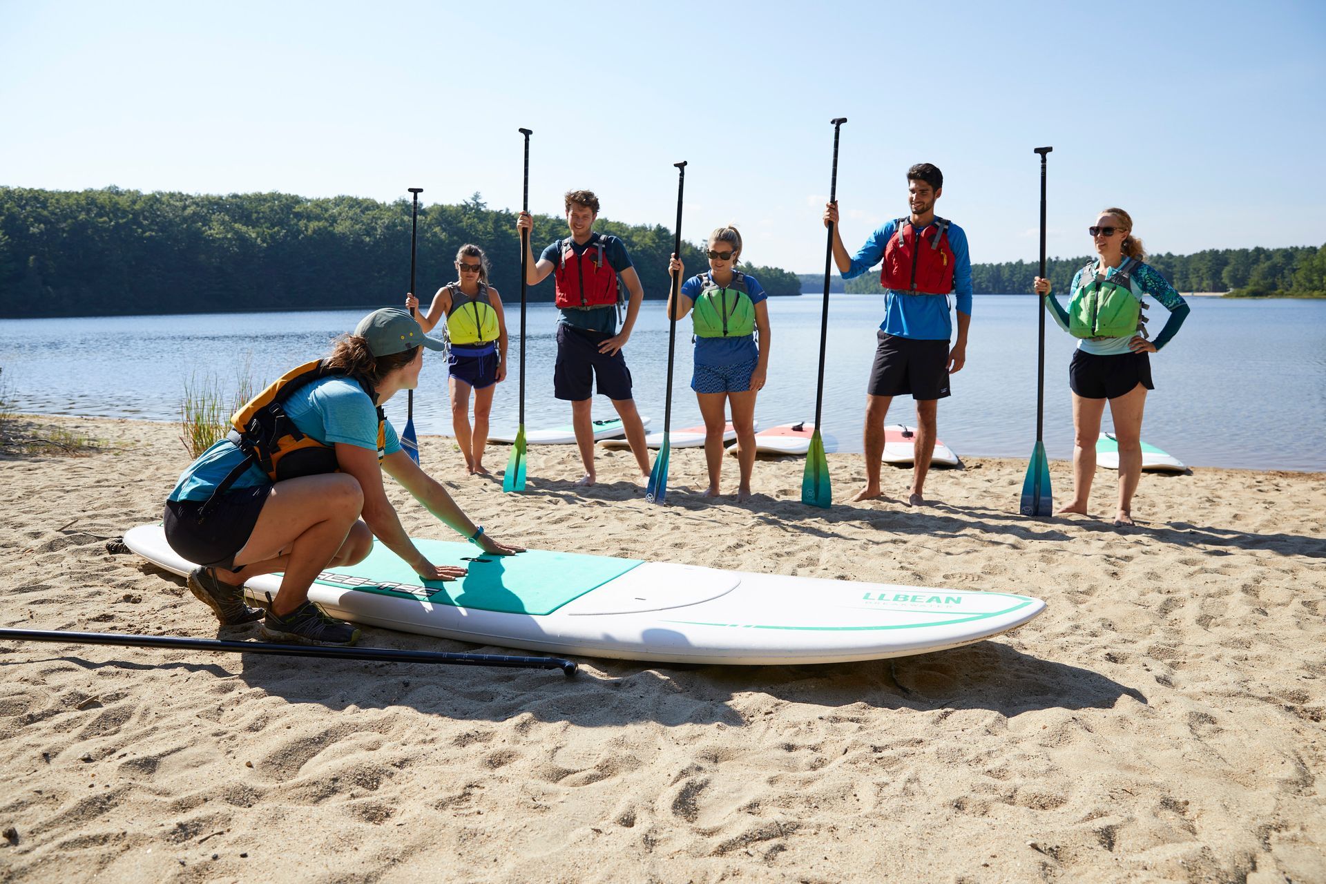 Paddleboarding instructor explaining to a class, where to position feet when standing on a paddleboard.