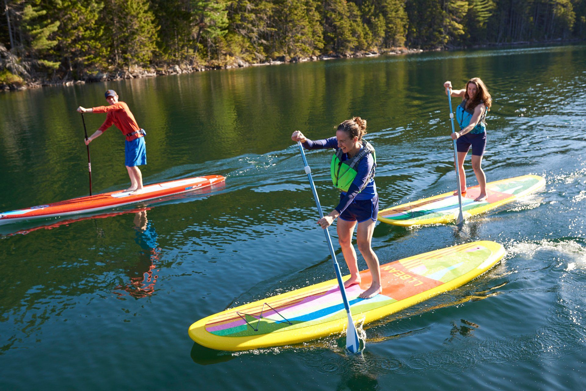 group of three paddleboarders paddling on a lake.