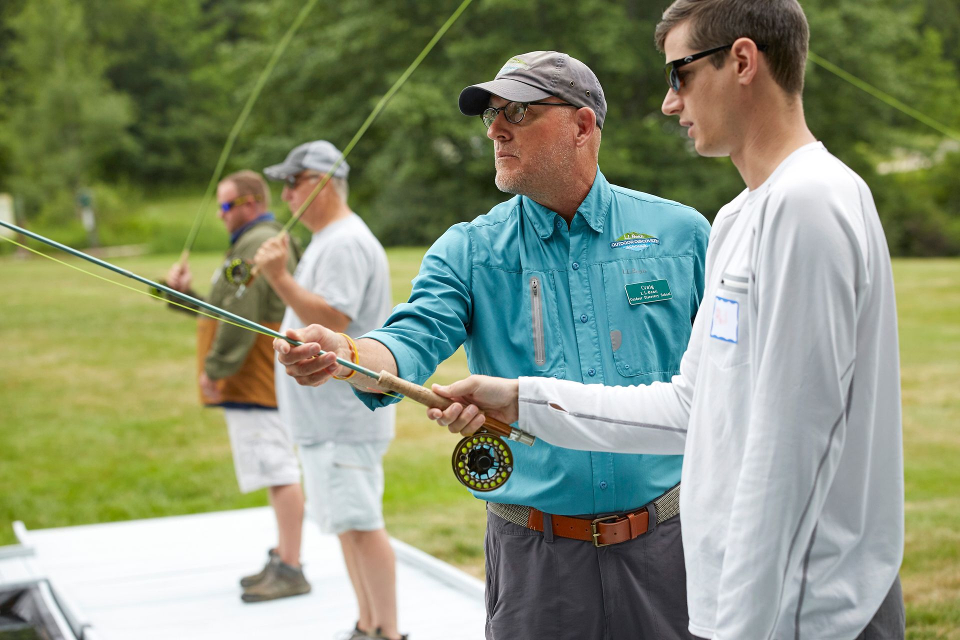 A fly casting instructor helping a student with their technique.