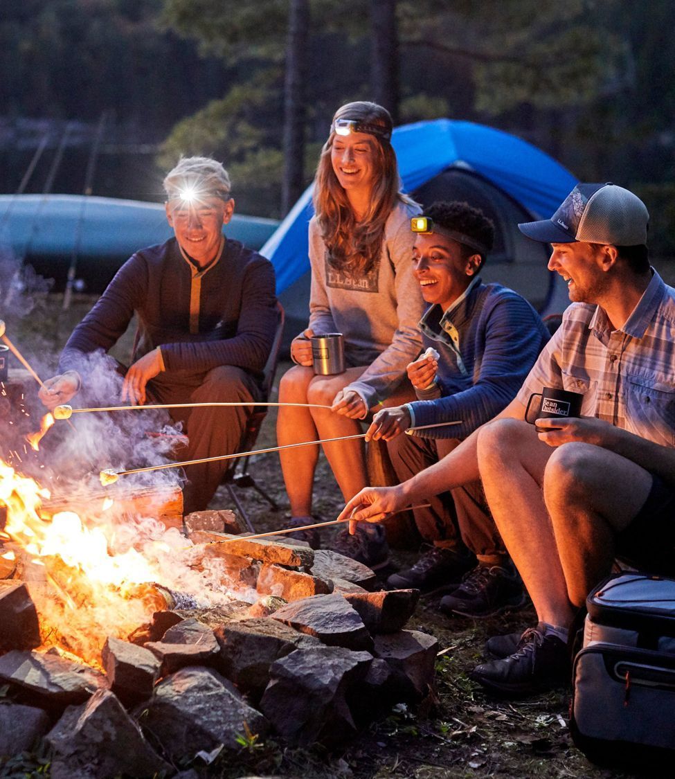 three adults sitting around a campfire, at night.