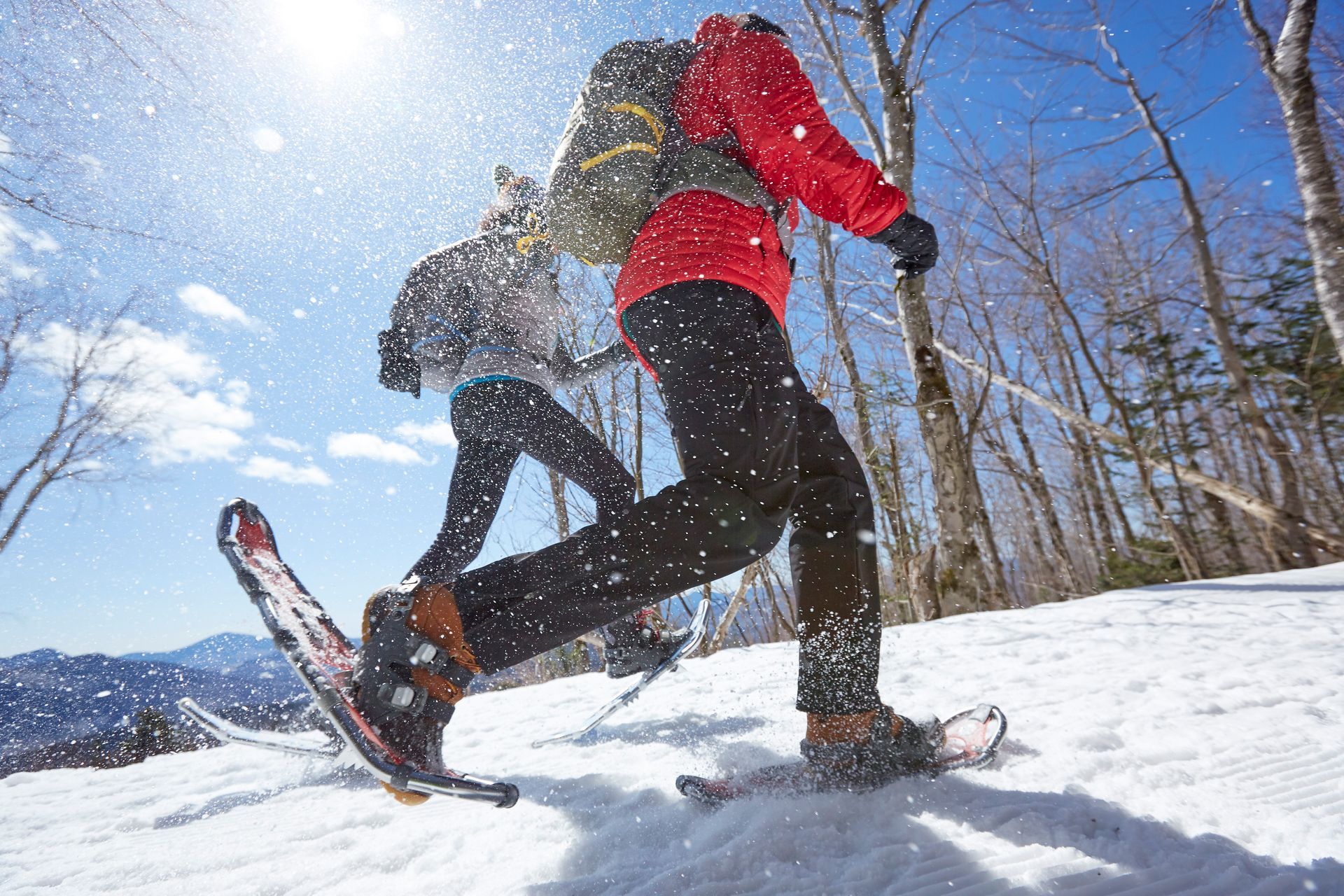 A woman and a man snowshoeing on a sunny day.