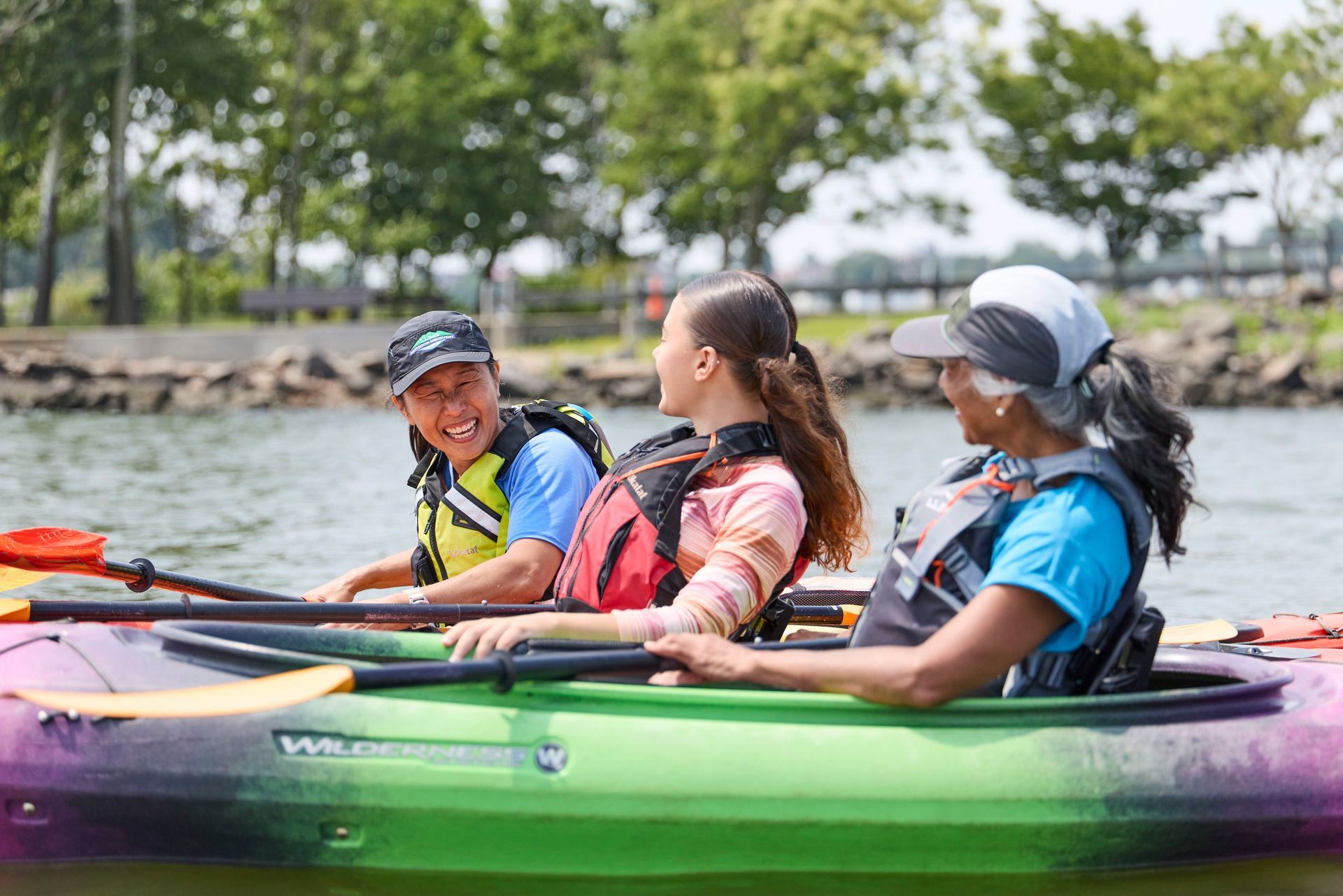 two women kayakers talking with their Outdoor Discovery Programs instructor, and smiling.