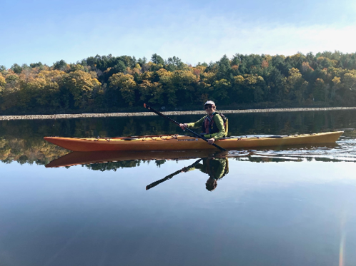 a women paddling a sea kayak on a lake.