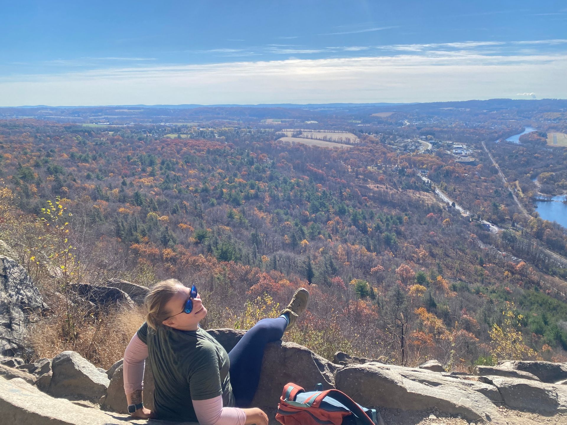 Program Coordinator, Corey S., smiling and relaxing on a rocky summit in the sun.