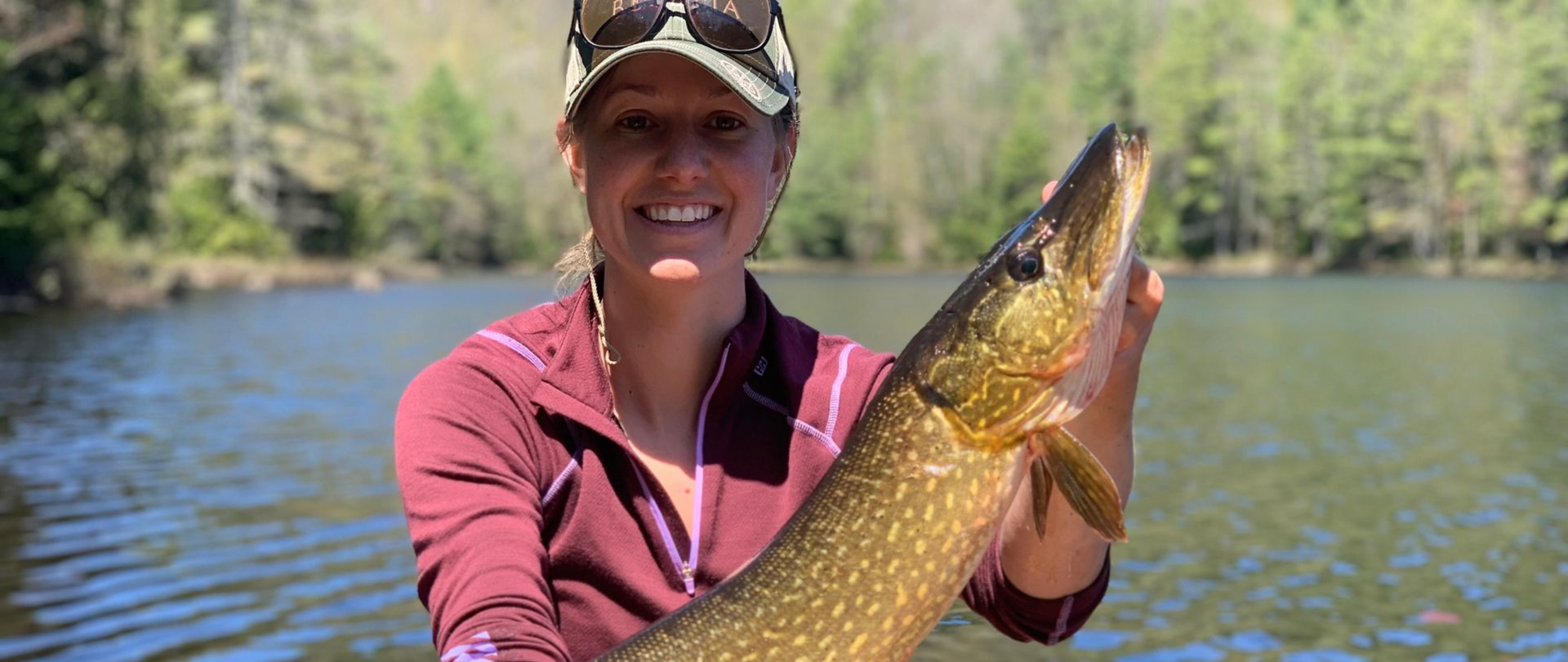 Women holding a Northern Pike caught while fly fishing.