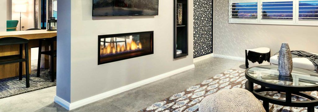 A see through fireplace in a living room area with an inbuilt bookcase and accent wall.