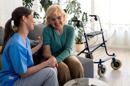 Female home care specialist and satisfied elderly woman holding hands
