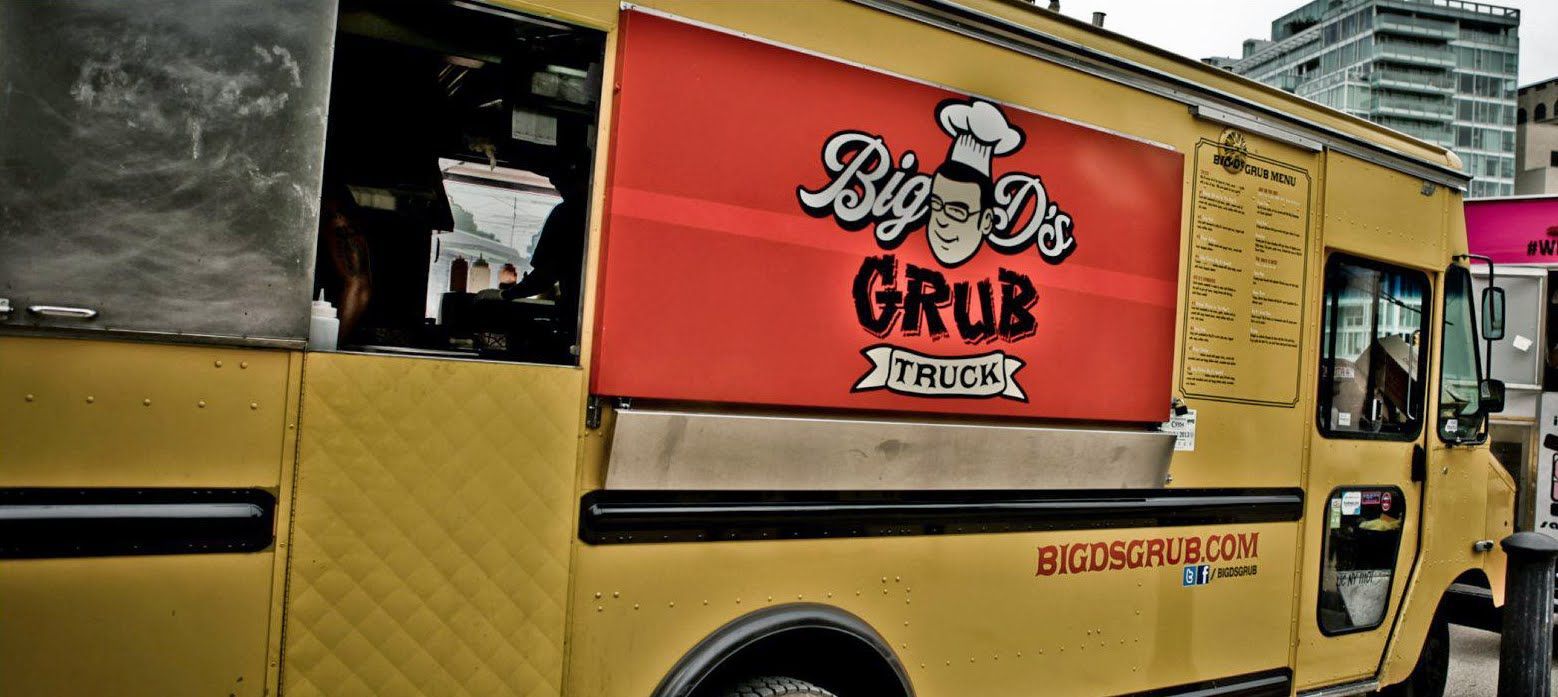 A yellow food truck is parked on the side of the road.