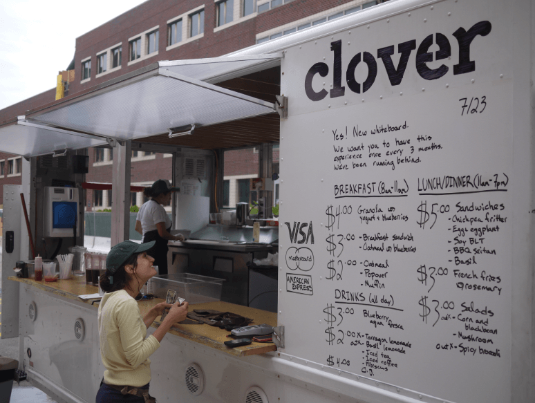 A woman standing in front of a clover food truck