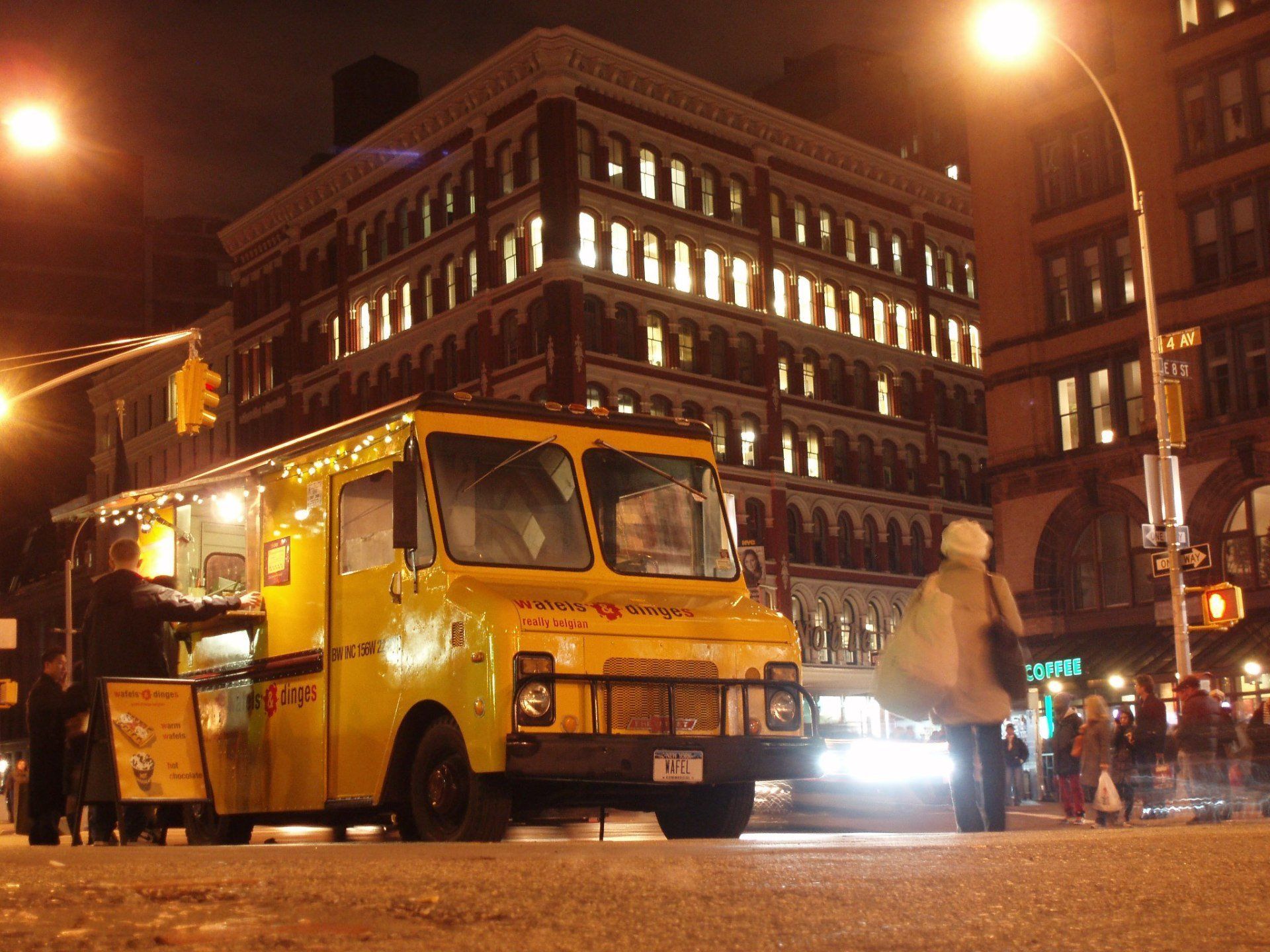 A yellow food truck is parked in front of a building