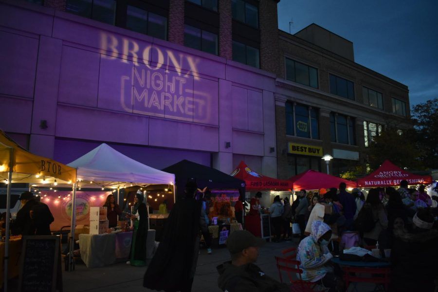 A group of people are standing in front of a bronx night market.