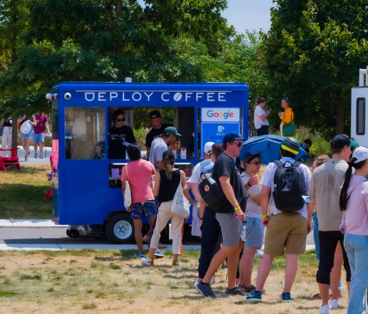 A group of people are standing in front of a blue coffee truck.