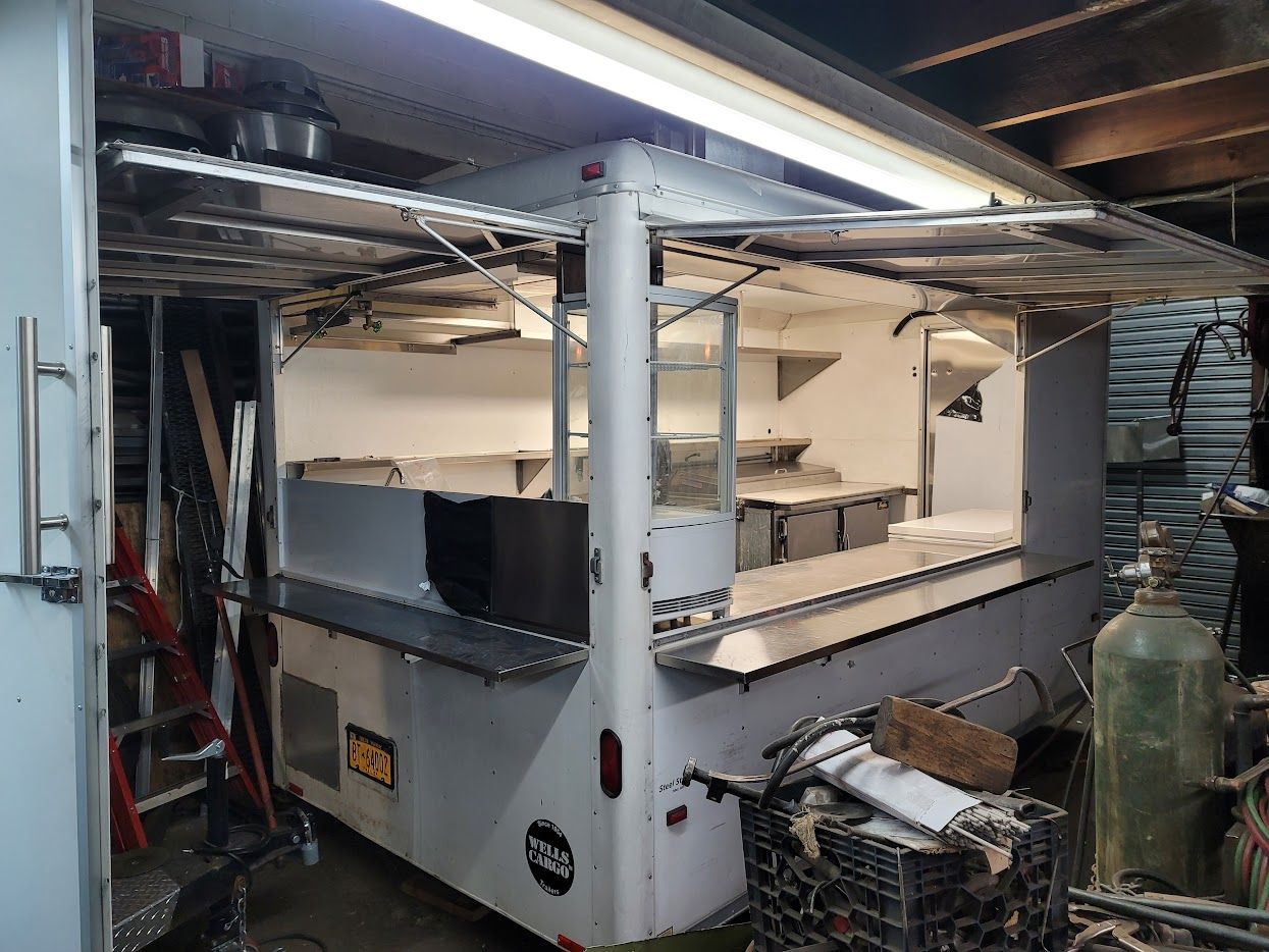 A food truck is parked in a garage with the door open.