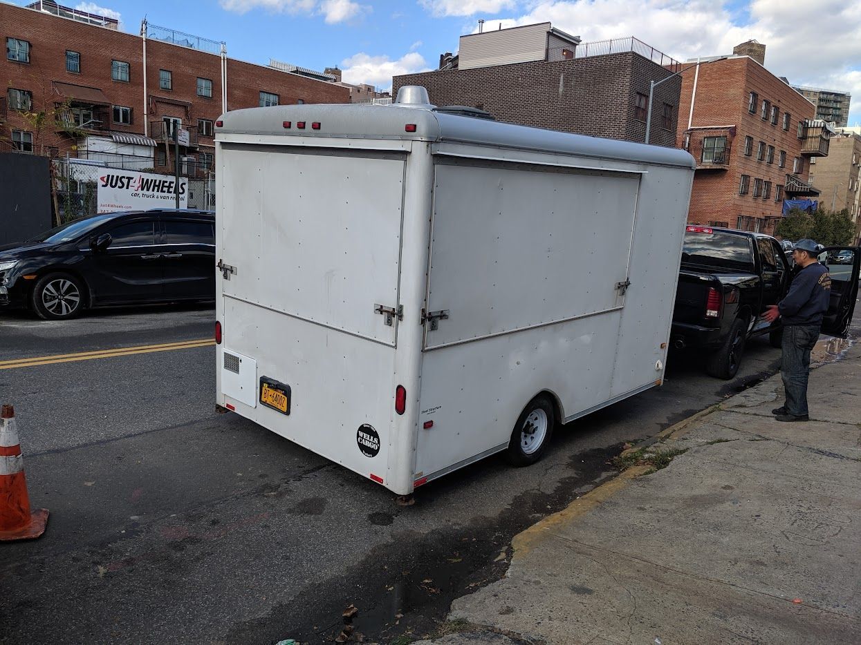 A white food truck is parked on the side of the road.