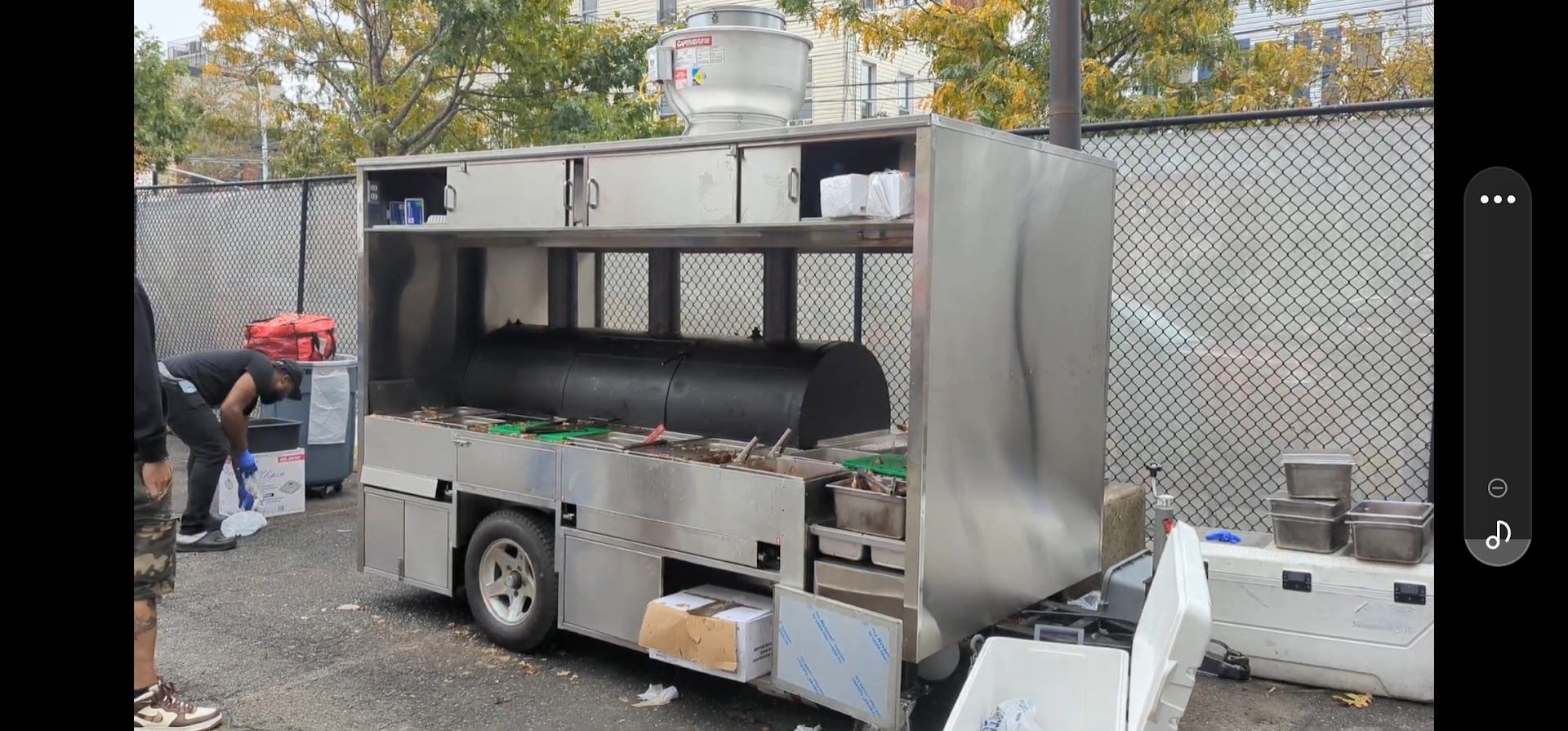 A man is standing next to a stainless steel food truck.