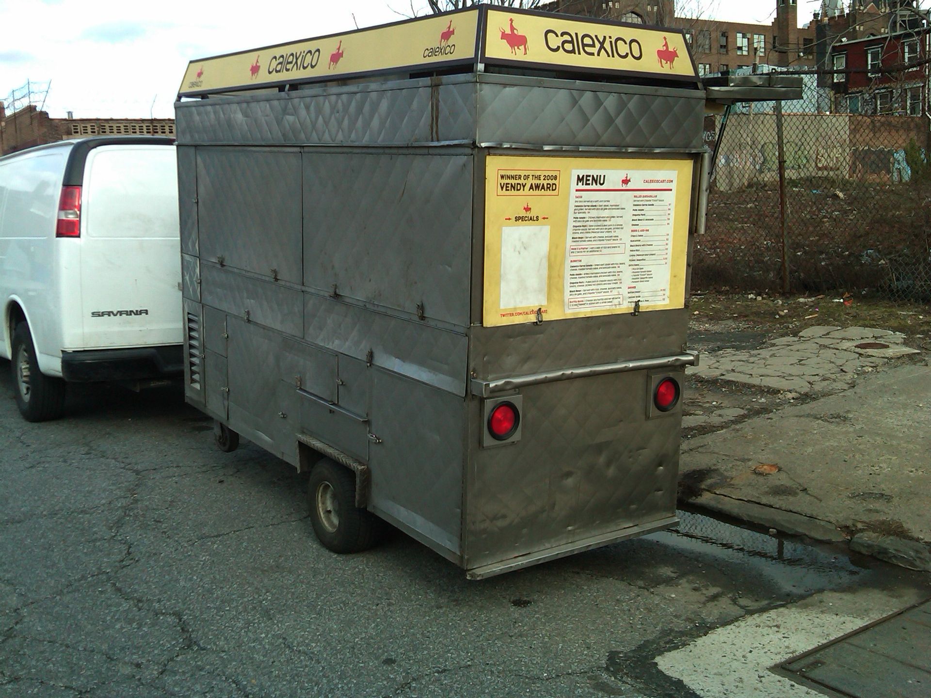 A white van is pulling a food truck that says calenco