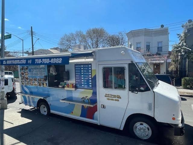 A white food truck is parked on the side of the road