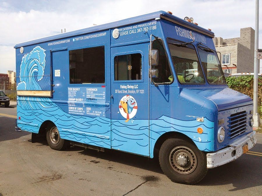 A blue food truck is parked on the side of the road.