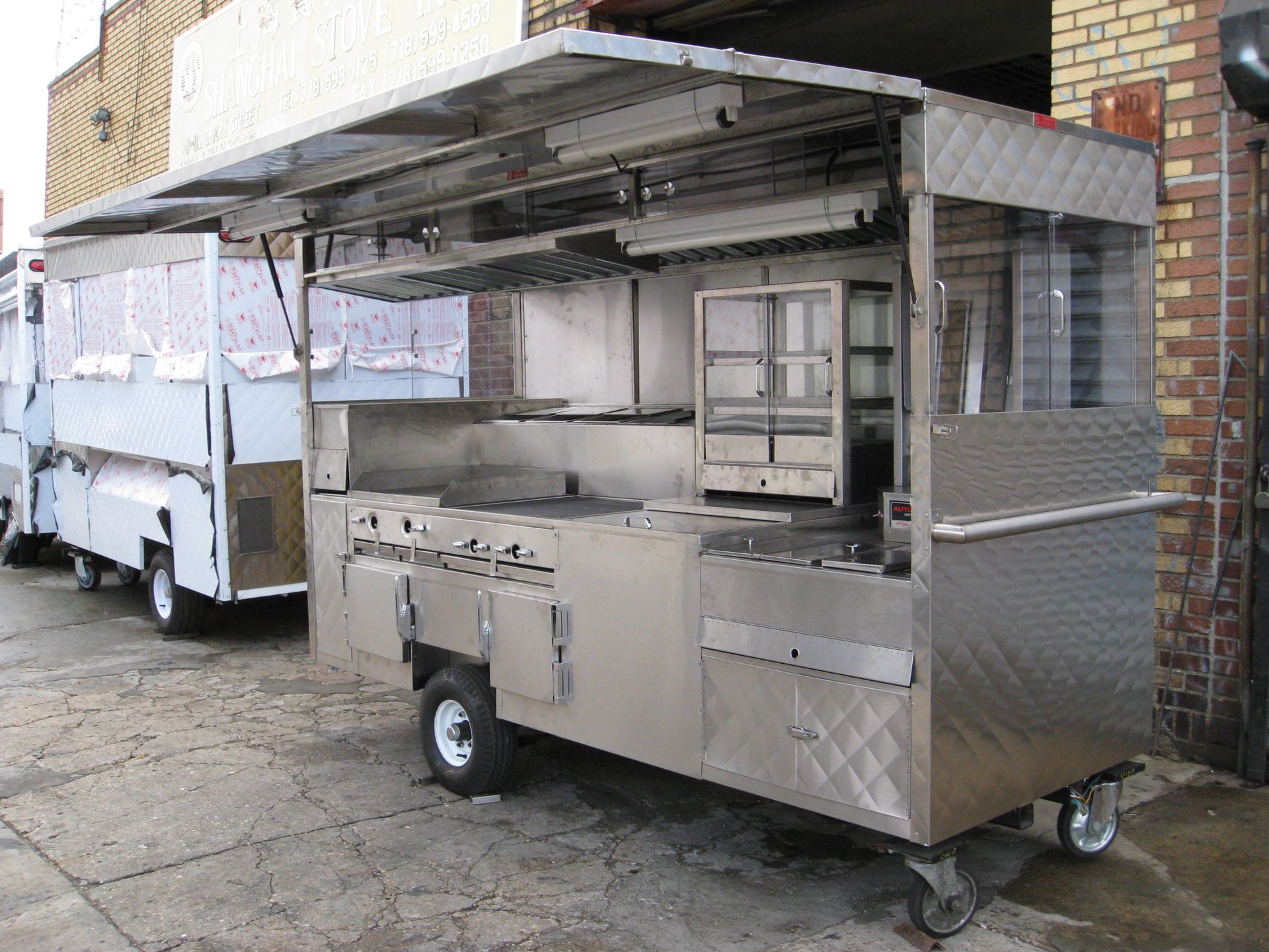 Two food trucks are parked in front of a brick building