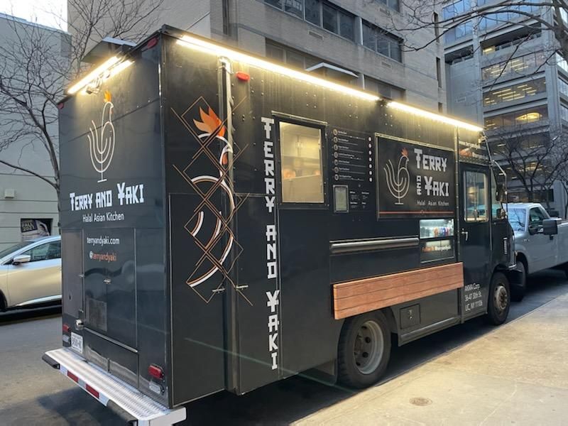 A food truck is parked on the side of the road.