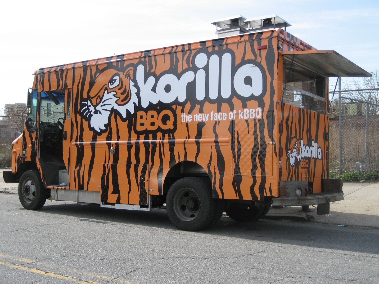 A food truck is parked on the side of the road in front of a building.