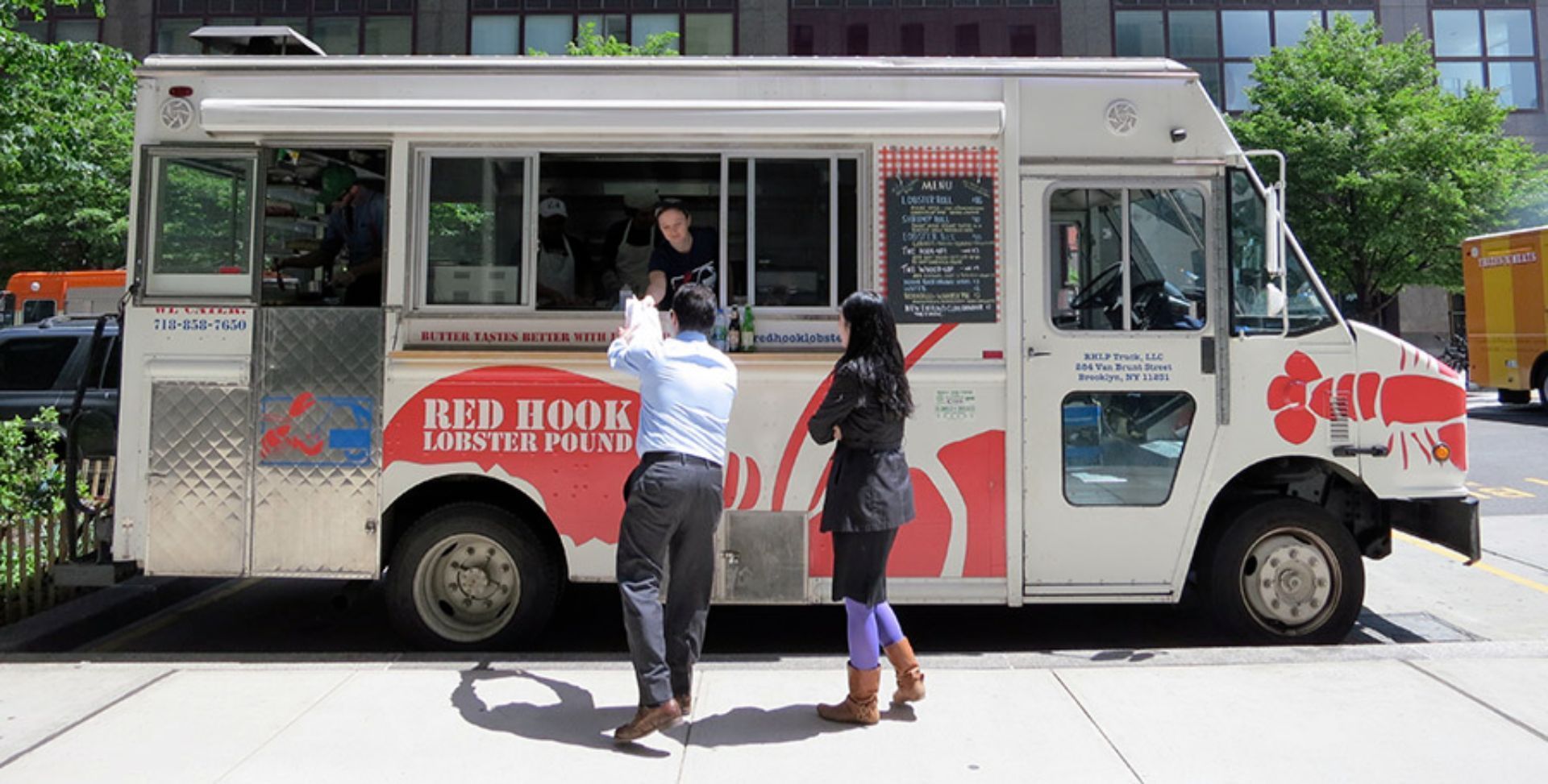 A man and woman are standing in front of a food truck that says bbq house