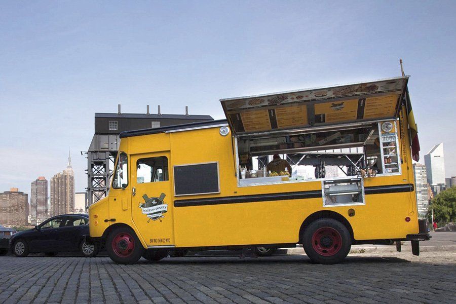 A yellow food truck is parked on the side of the road