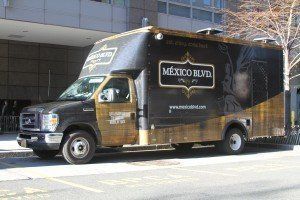 A food truck is parked on the side of the road in front of a building.