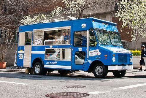 A blue food truck is parked on the side of the road.