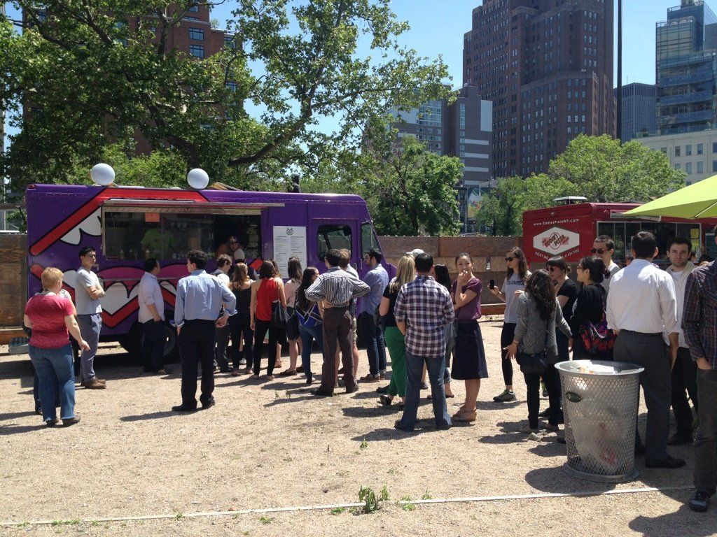 A group of people standing in front of a purple food truck