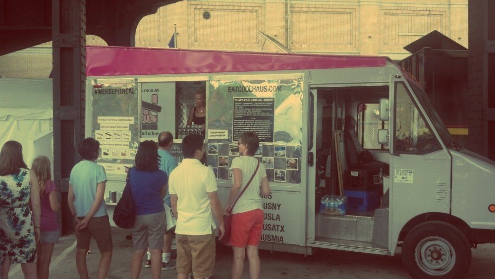 A group of people are standing in front of a food truck.