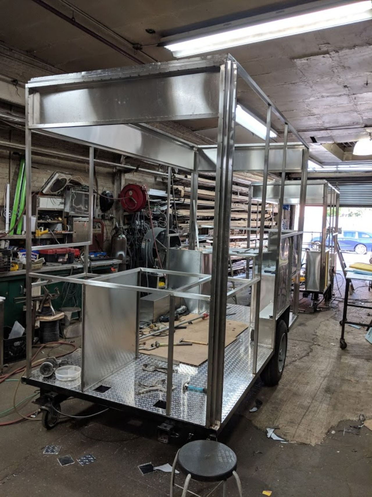 A stainless steel trailer is being built in a garage.