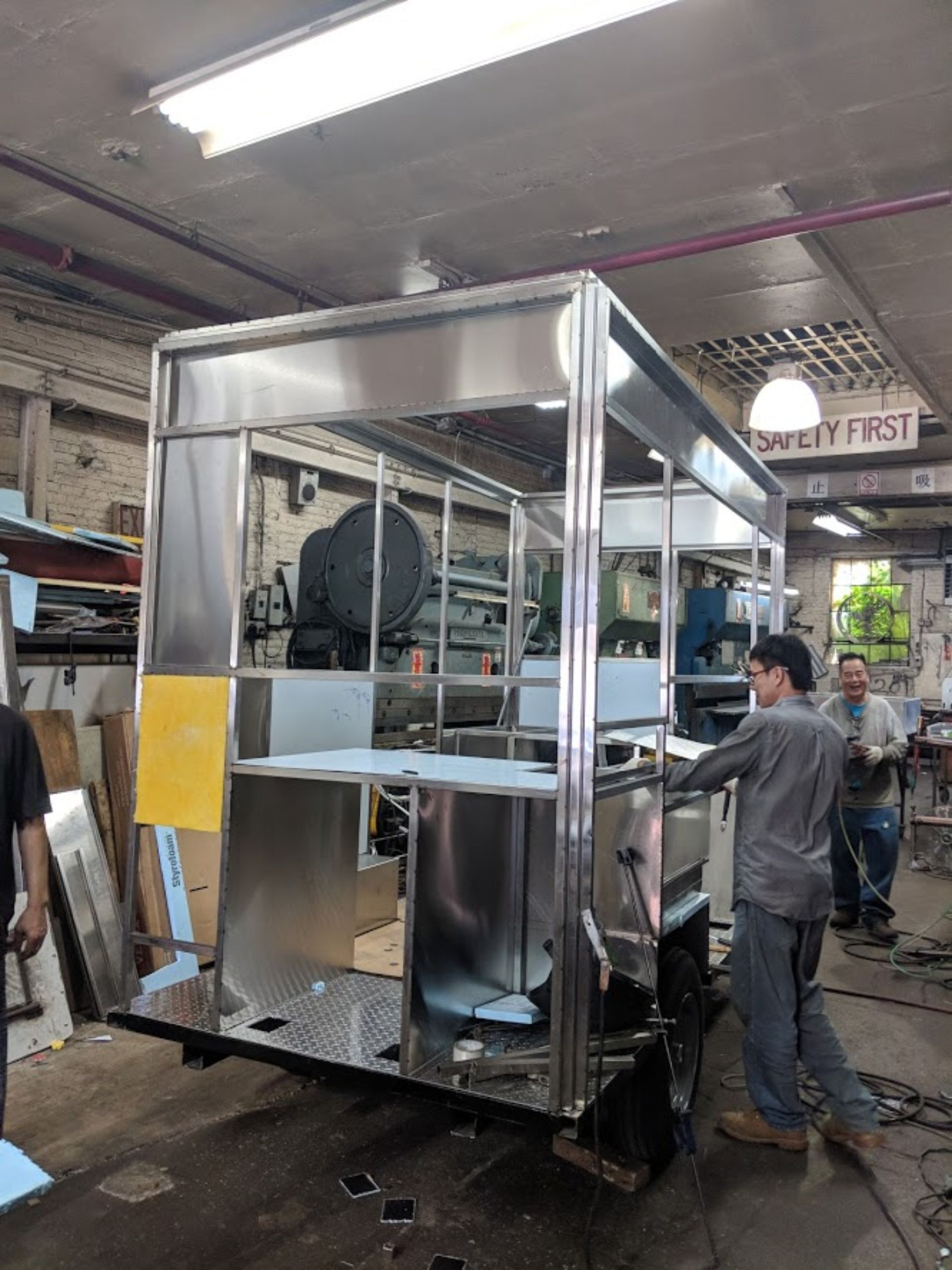 A man is working on a stainless steel structure in a factory.
