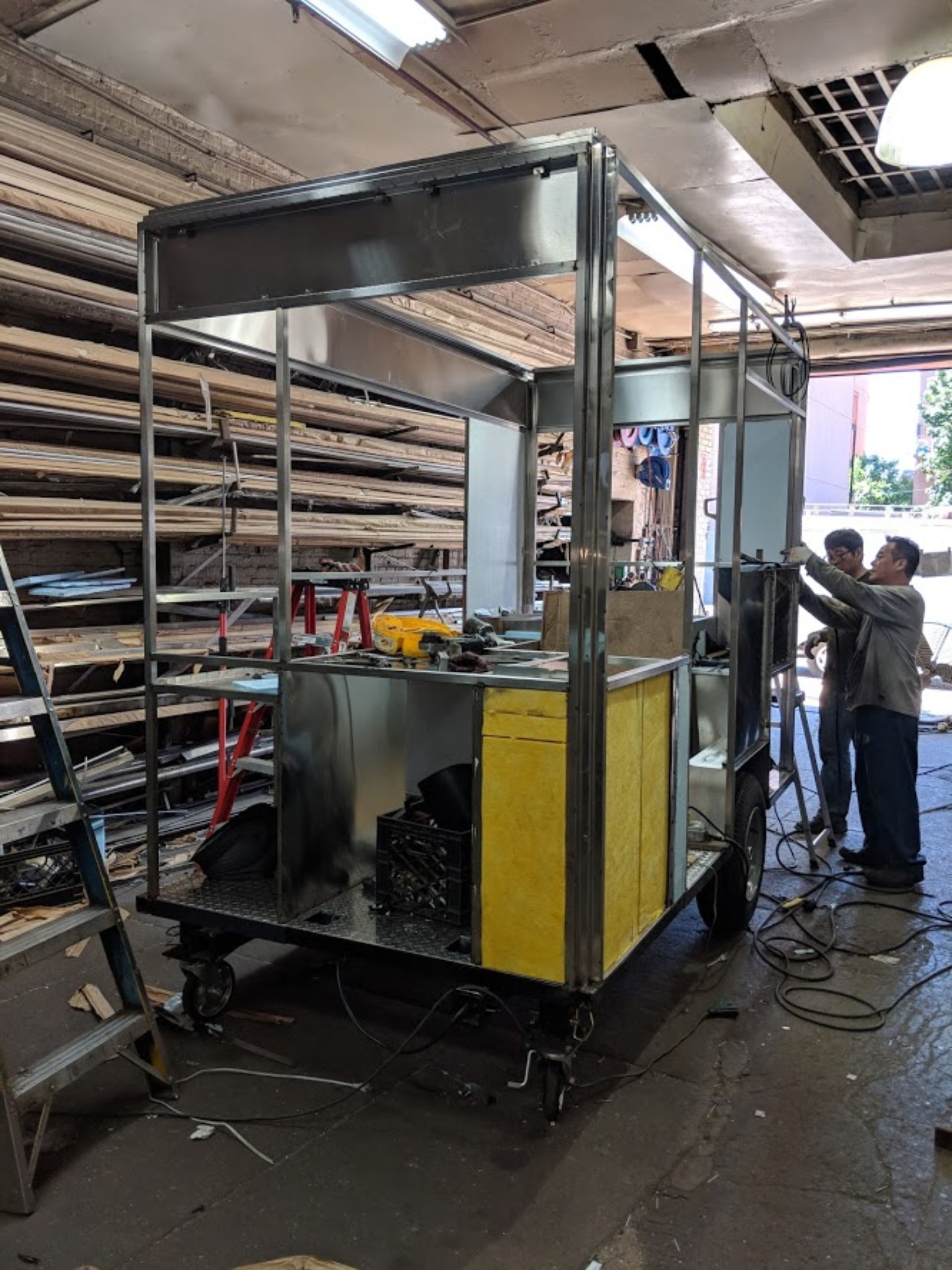 Two men are working on a metal structure in a garage